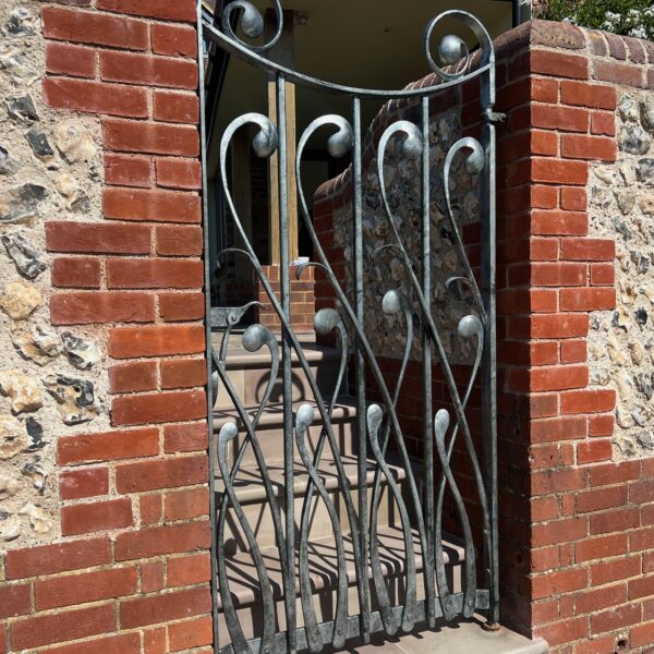 Sculptural gate in hand forged wrought iron with an organic fluid design based upon plants