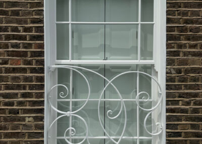 bespoke decorative wrought iron security grille on asash window in a period house in Primrose Hill, North London