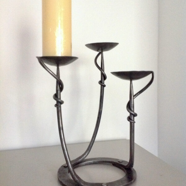 modern wrought iron candlestick with a round base and candles of different heights